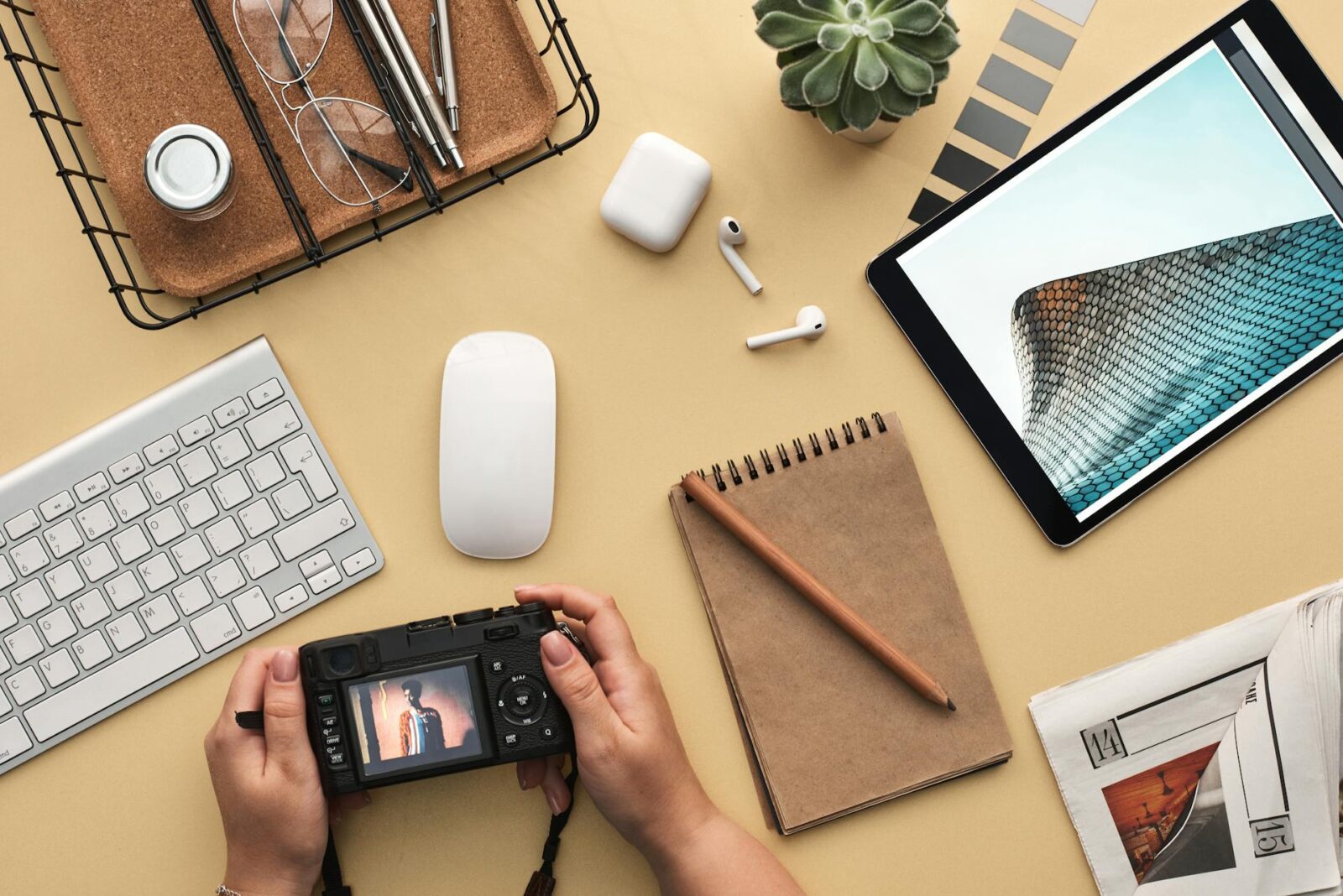 A beautiful 4K Cool Wallpaper with a camera, rough pen, mouse, keyboard on a table with a light yellow background.