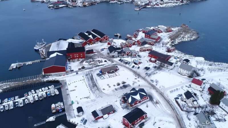 Snow-draped village seen from above, with white rooftops and serene streets creating a picturesque winter scene.