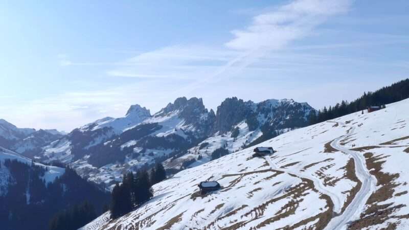 A scenic view of a snow-covered mountain range with a winding road traversing through the landscape.