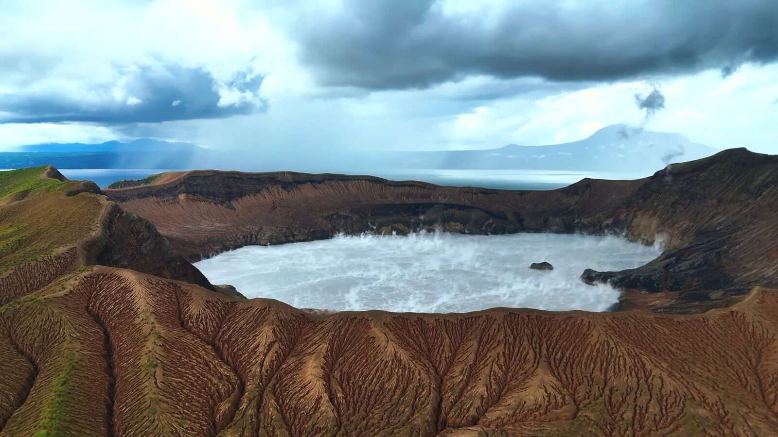 A giant crater located in the center of a majestic mountain landscape that showcases rugged terrain and natural beauty, Wonders of the World Pictures.
