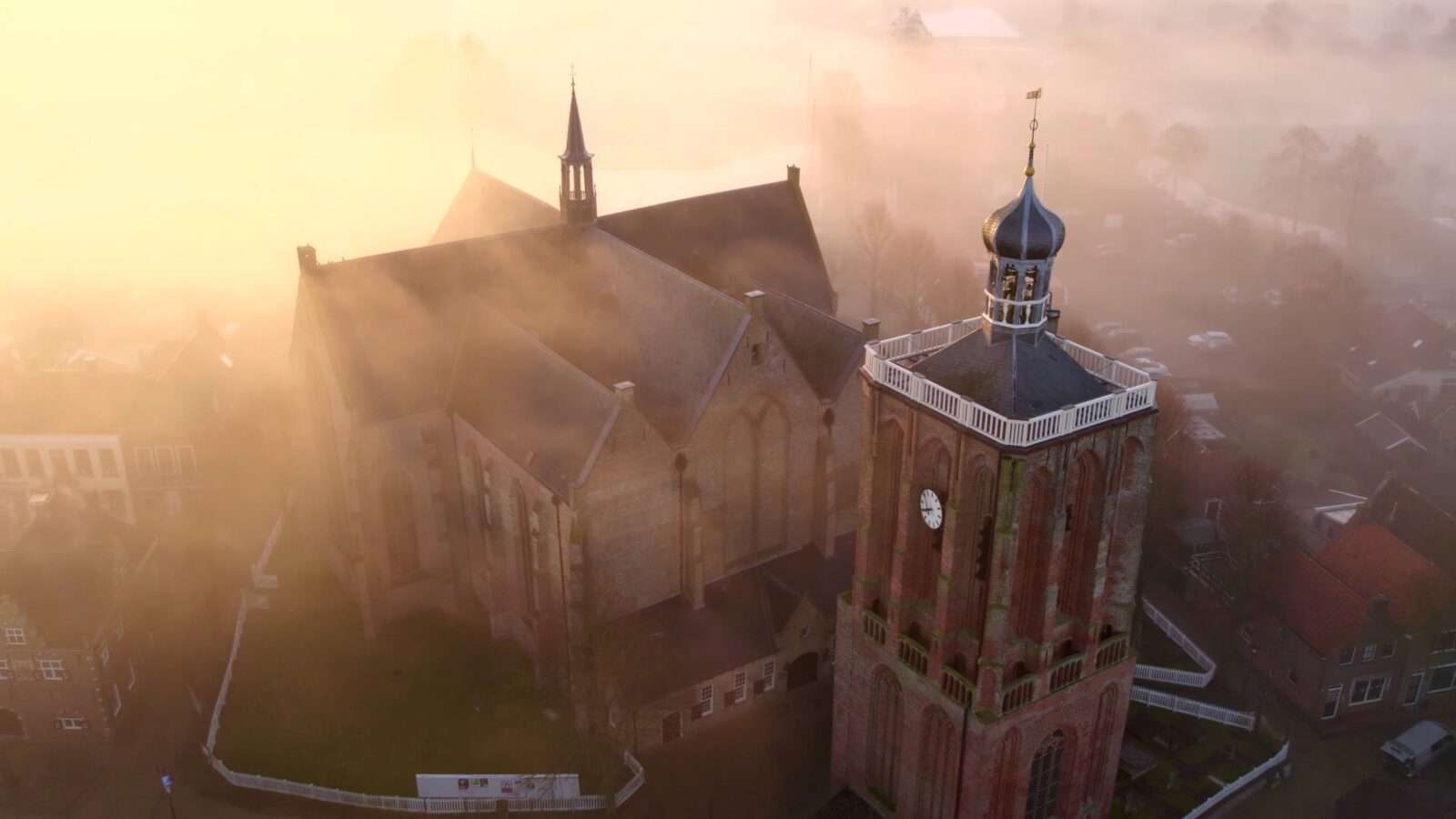 Beautiful view of the church with its bell tower surrounded by morning mist at sunrise, Wonders of the World Pictures.
