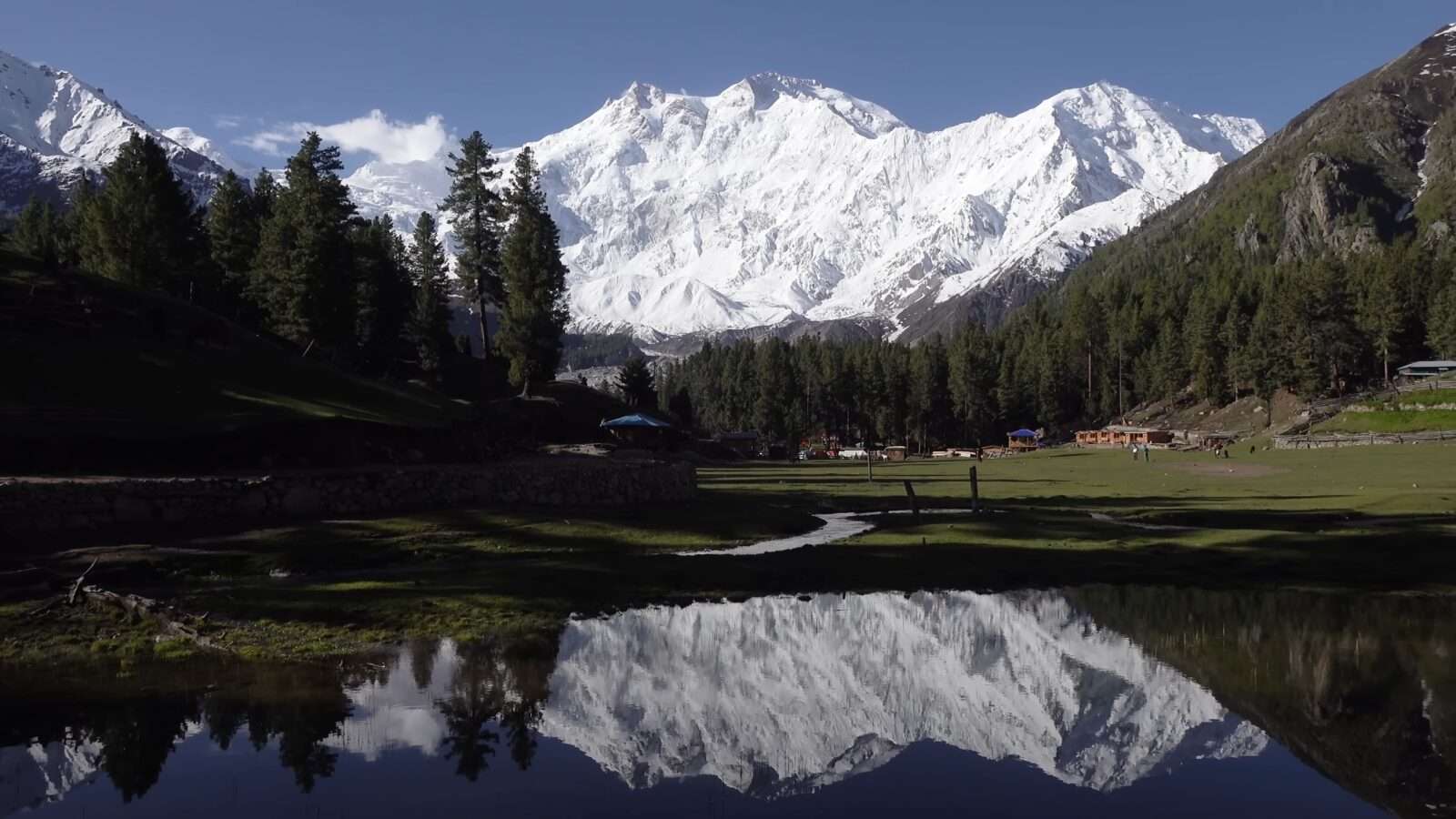 The reflection of a hill range is clearly visible in a pond, an amazing sight of natural beauty, Wonders of the World Pictures.
