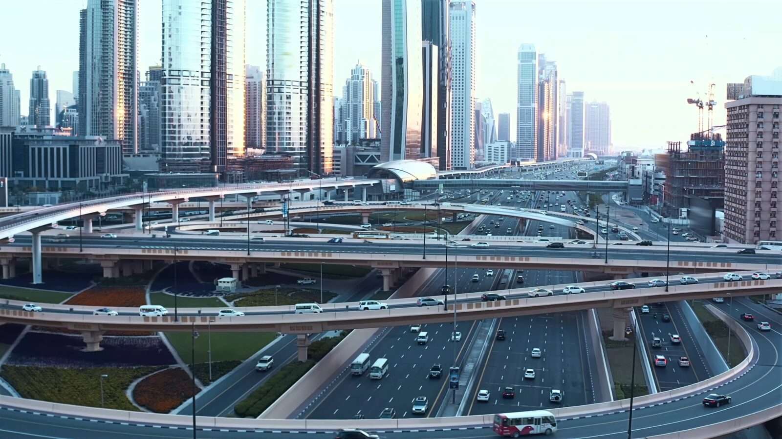 A busy multi-level highway interchange with surrounding skyscrapers at dusk, Wonders of the World Pictures.
