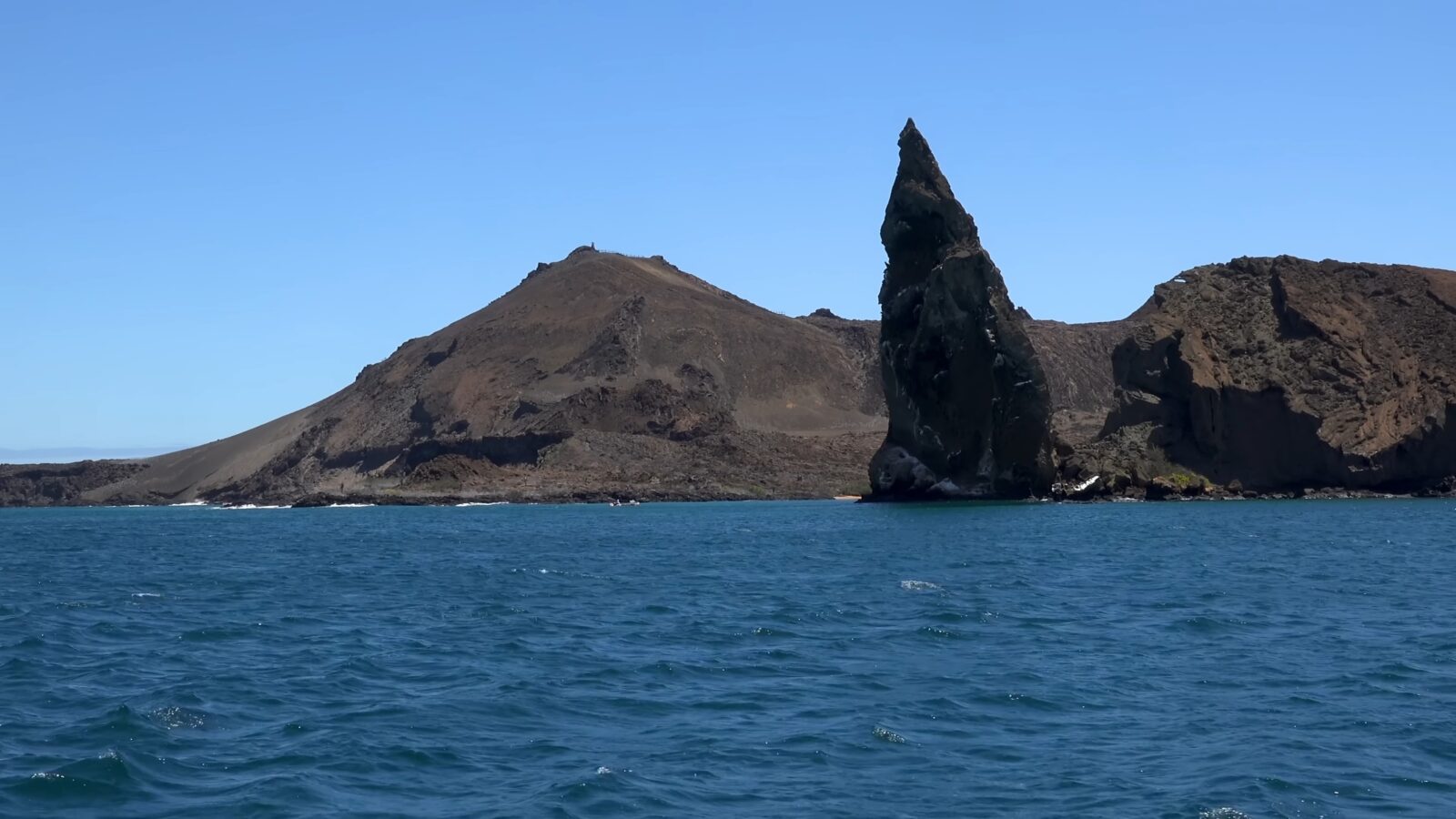 A rock formation in the sea, located near a mountain, presents a wonderful example of natural beauty, Wonders of the World Pictures.