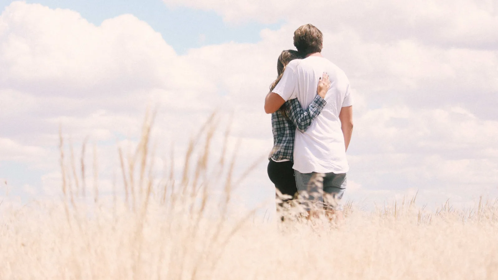 Love couple standing in the grass field