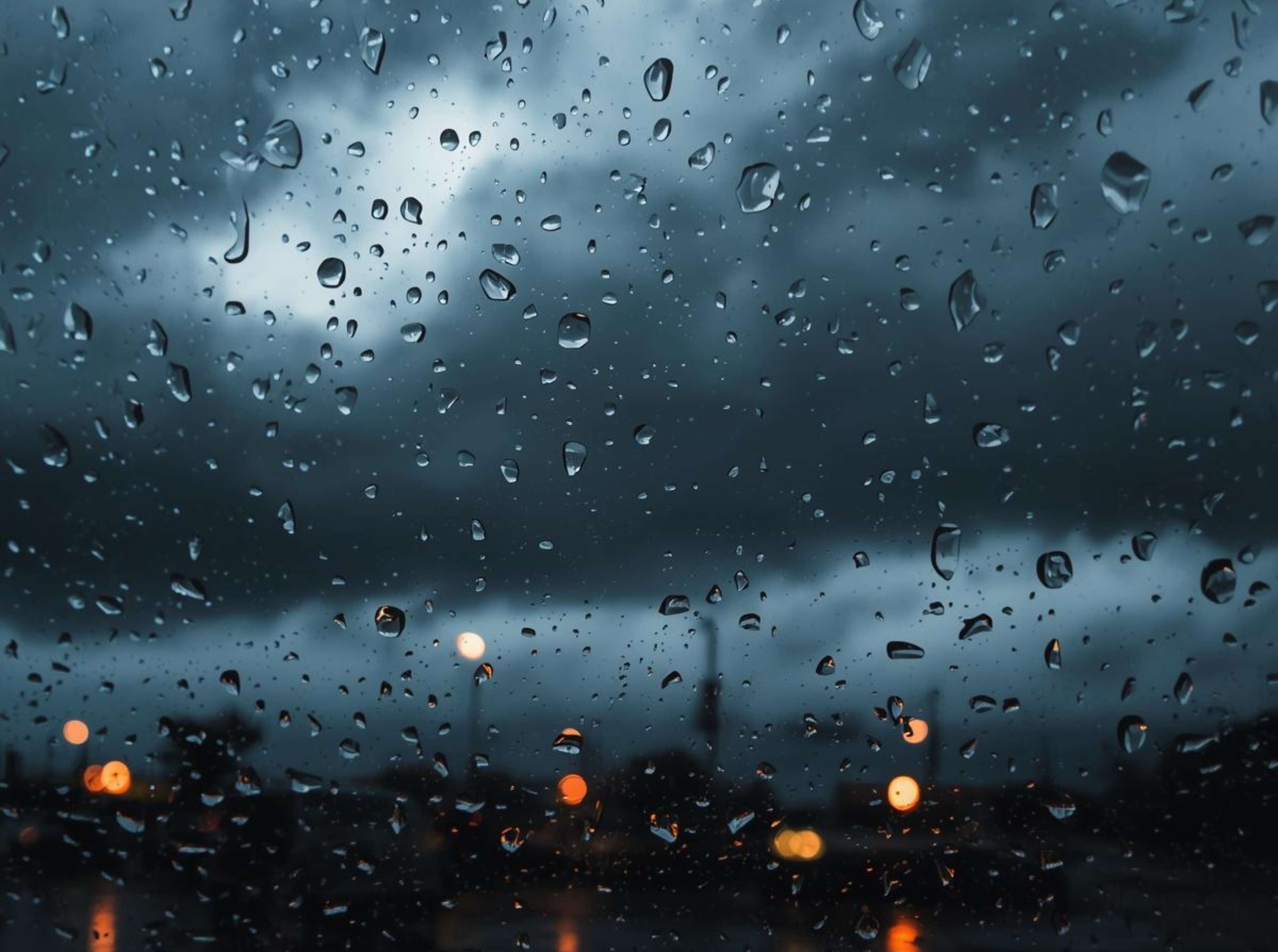 Free 4K image of raindrops on a window with moody background.